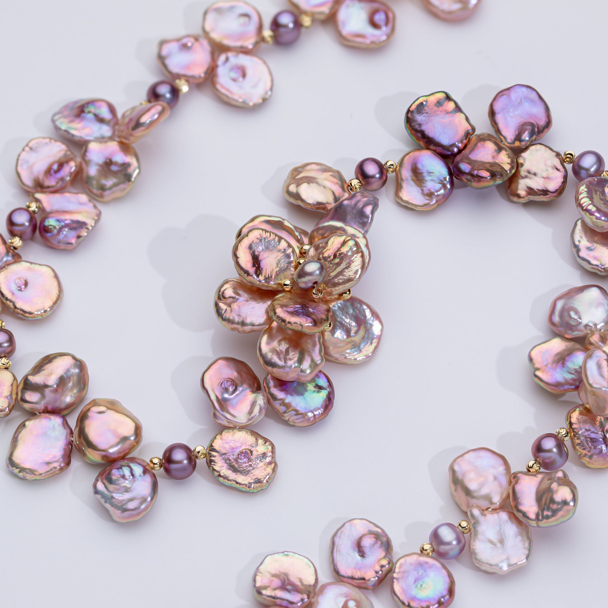 A necklace with pink pearl-like beads and gold-tone metal components, arranged in a floral pattern.