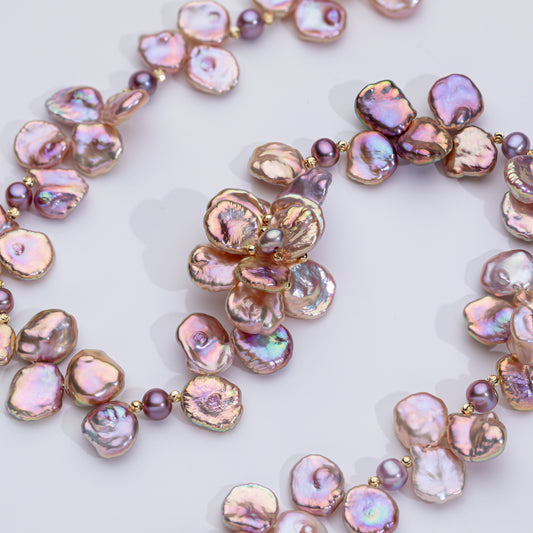 A necklace with pink pearl-like beads and gold-tone metal components, arranged in a floral pattern.