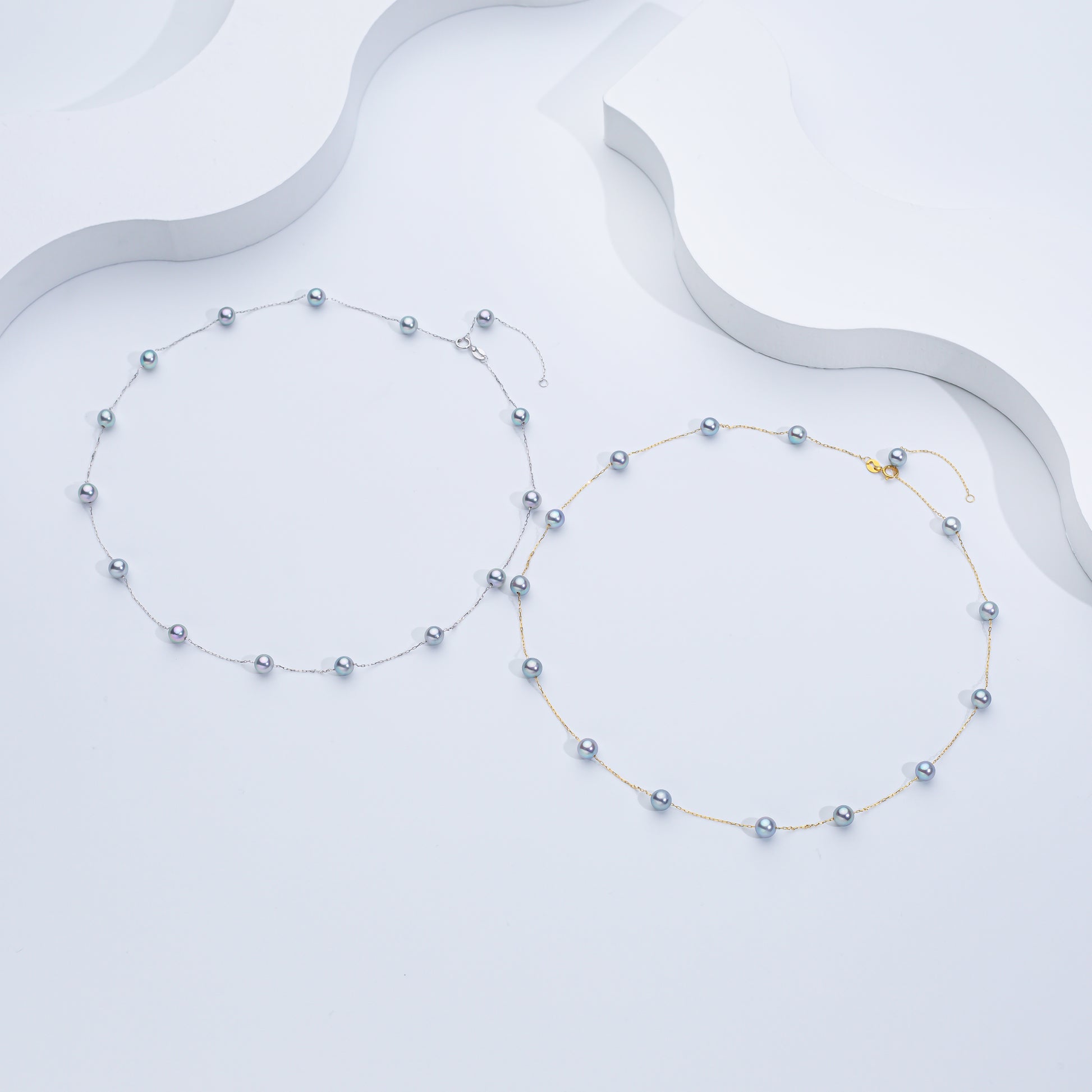 Two Akoya sea pearl necklaces with sterling silver, one with a floating pearl design and the other with pearls strung on a chain, displayed against a white background.